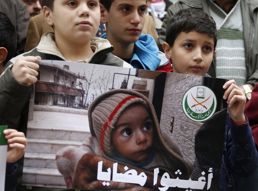 Mitglieder der Gruppe «Jemaah Islamiyah» halten ein Plakat mit einem hungernden syrischen Kind, um vor dem Internationalen Komitee des Roten Kreuzes in Beirut auf die Leiden der Menschen in der syrischen Stadt Madaja aufmerksam zu machen.<br data-editable="remove">