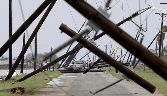 FILE - In this Aug. 26, 2017 file photo, a driver works his way through a maze of fallen utility poles damaged in the wake of Hurricane Harvey in Taft, Texas. Hurricane Harvey roared onto the Texas sh ...