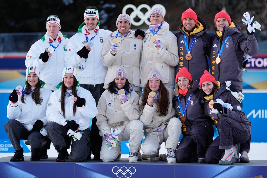 Team Italy, silver medalists, from left, Team France, gold medalists, and Team Germany, bronze medalists pose after the 4X6-kilometer mixed relay biathlon race at the 2026 Winter Olympics in Anterselv ...