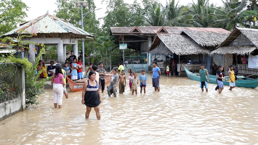 epa06403710 Filipino villagers wade on floodwater in flood hit town of Salvador, Lanao del Norte province, Philippines, 23 December 2017. According to news reports, Tropical storm Tembin brought mudsl ...