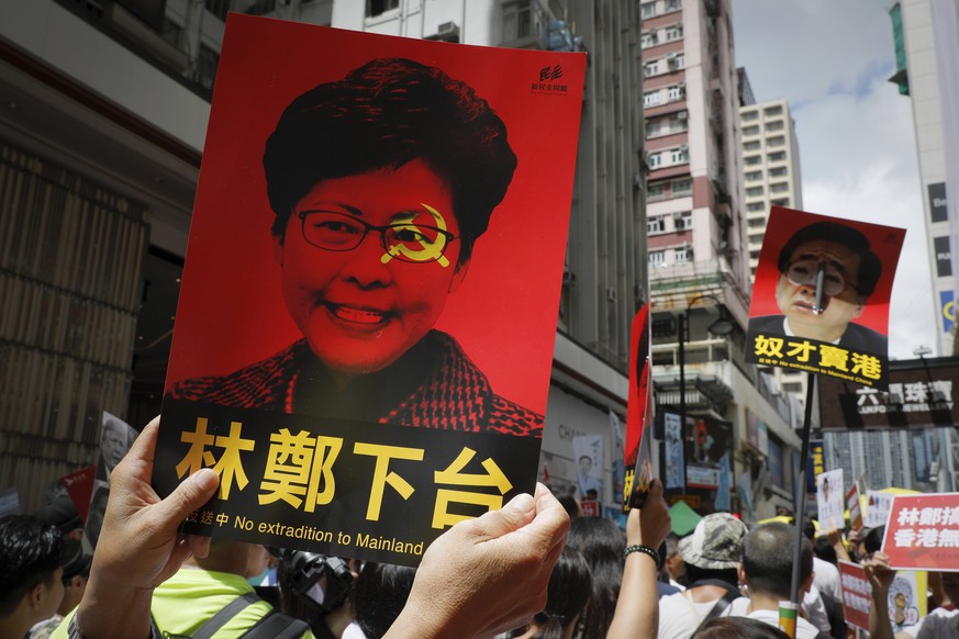 Demonstranten halten Plakate mit dem Porträt von Regierungschefin Lam in die Höhe. 