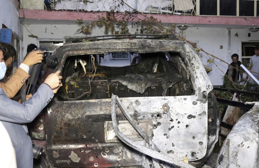 Afghan journalists take a photos of destroyed vehicle inside a house after U.S. drone strike in Kabul, Afghanistan, Sunday, Aug. 29, 2021. A U.S. drone strike destroyed a vehicle carrying &quot;multip ...