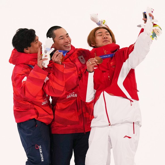 From left, silver medalist Japan's Ryoma Kimata, gold medalist Japan's Kira Kimura and bronze medalist China's Su Yiming take a selfie after the men's snowboarding big air finals a ...