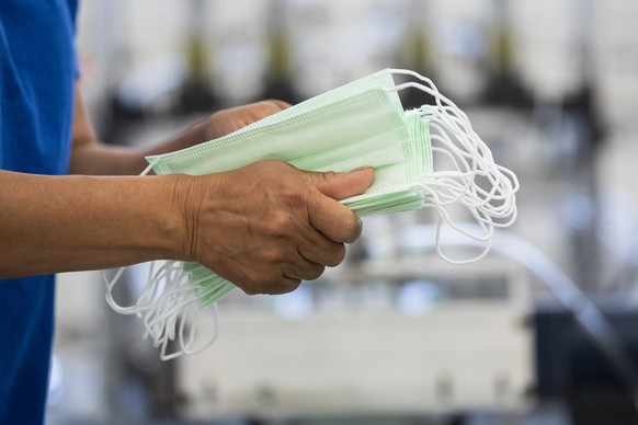 Mitarbeiter verarbeiten die Schutzmasken, die chirurgischen OP-Masken Typ II R, bei dem Verbandsstoffhersteller Wernli AG in Rothrist, aufgenommen am Dienstag, 28. April 2020. (KEYSTONE/Ennio Leanza)