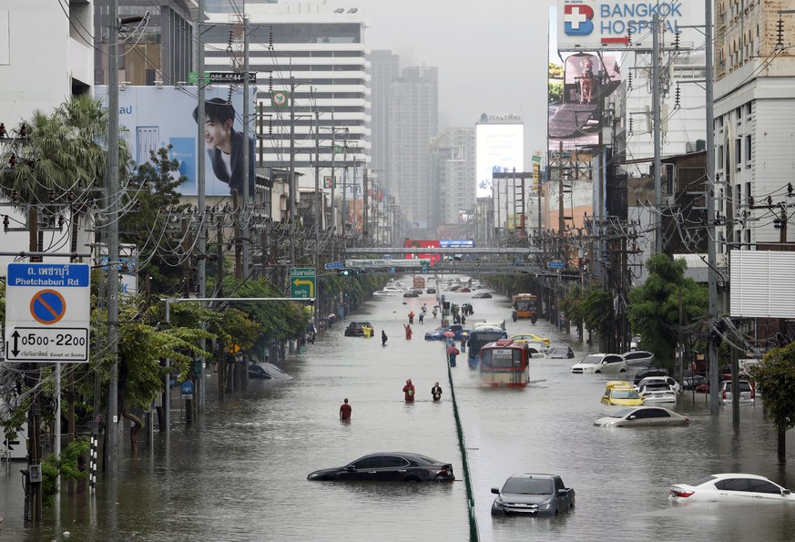 KEYPIX - epa13264029 Residents wade through floodwater as vehicles remain submerged along Phetchaburi Road in Bangkok, Thailand, 26 September 2026. All 50 districts in Bangkok have been declared flood ...