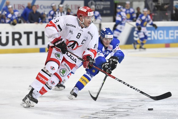 Yekaterinburg&#039;s Alexei Mikhnov, left, fights for the puck with Davos&#039; Dario Simion, during the game between HC Davos and Avtomobilist Yekaterinburg, at the 90th Spengler Cup ice hockey tourn ...