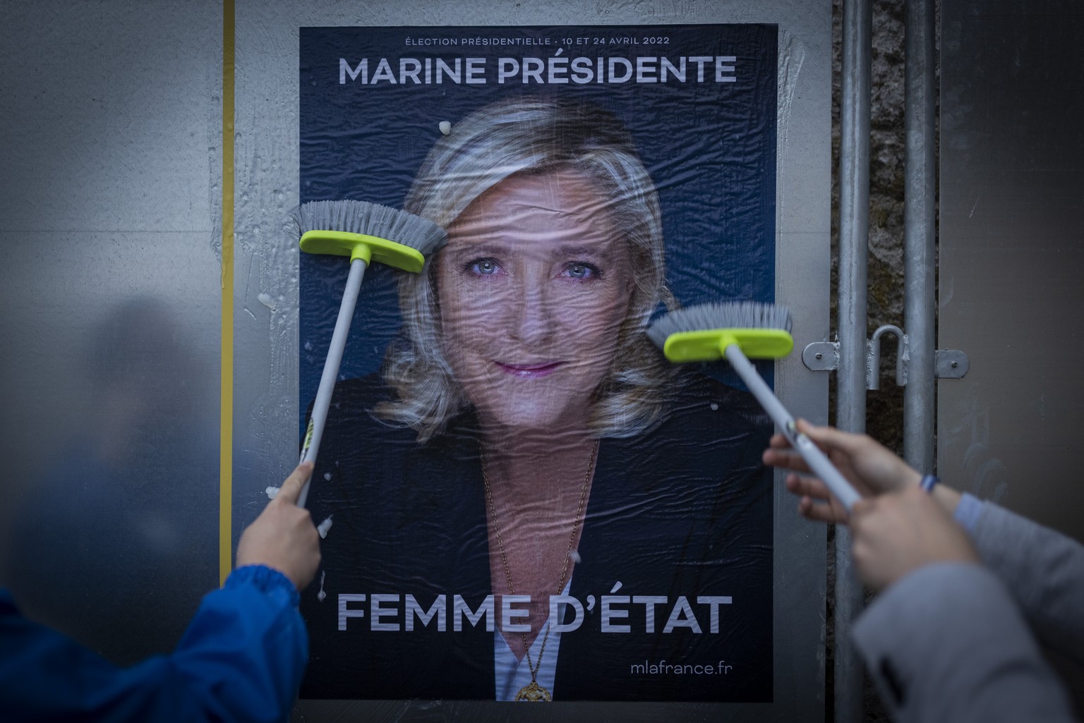 Bastian Maldiney and Emma Mino stick electoral poster of French far-right presidential candidate Marine Le Pen, Tuesday, March 29, 2022 in Vigneux-De-Bretagne, western France. France&#039;s first roun ...