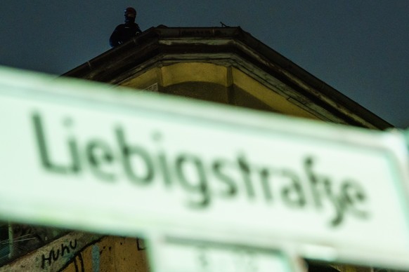 epa08730248 A police officer stands on top the building behind a street name plate a day prior to the planned eviction of the left-wing scene living project Liebig34 (Liebig street 34) in Berlin, Germ ...