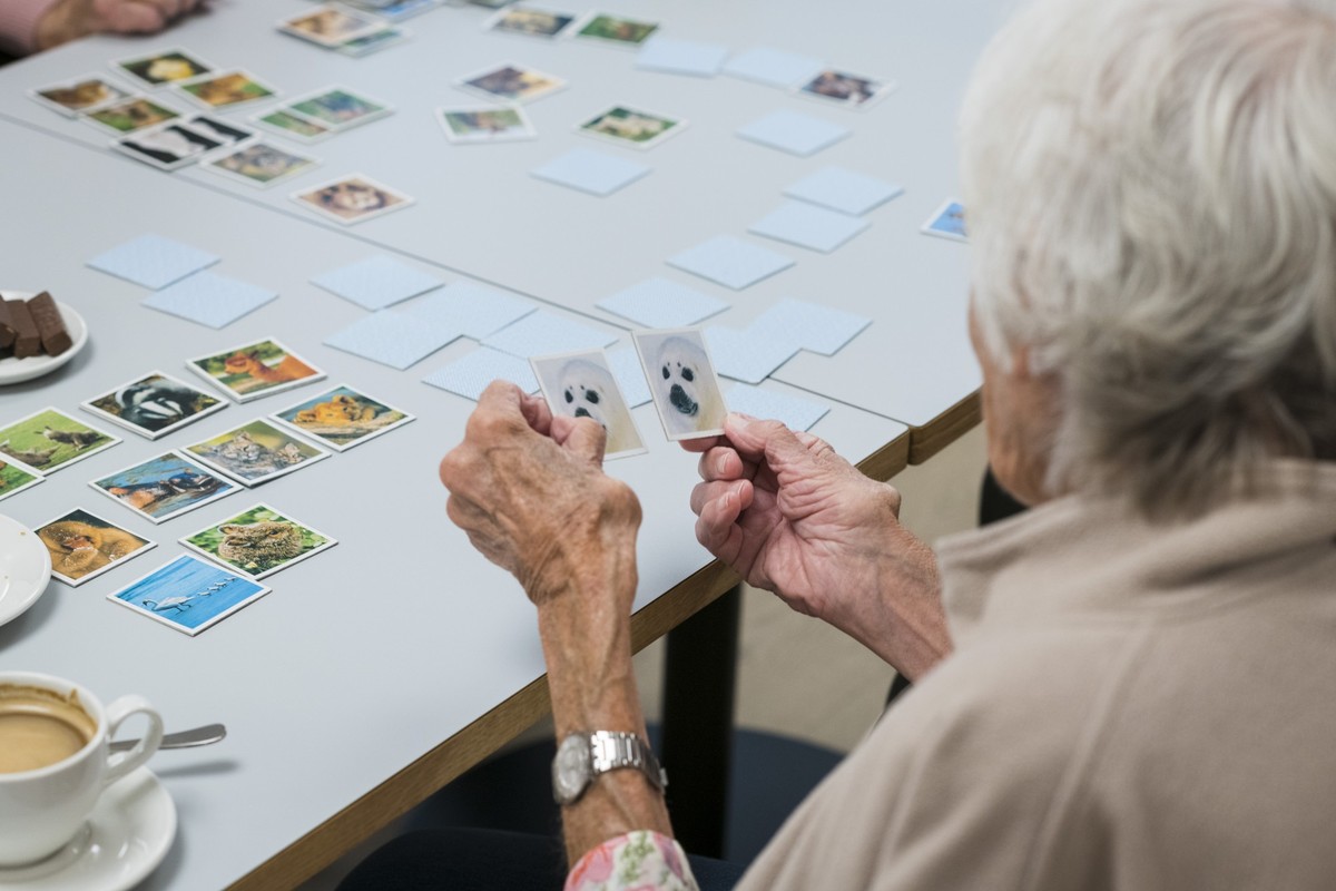 *** ACHTUNG REDAKTIONEN: BILD DARF NUR IN ZUSAMMENHANG MIT DEM THEMA DEMENZ UND DER PFLEGE VON DEMENZKRANKEN PERSONEN VERWENDET WERDEN *** Eine demenzkranke Bewohnerin schaut sich Memorykarten an mit  ...