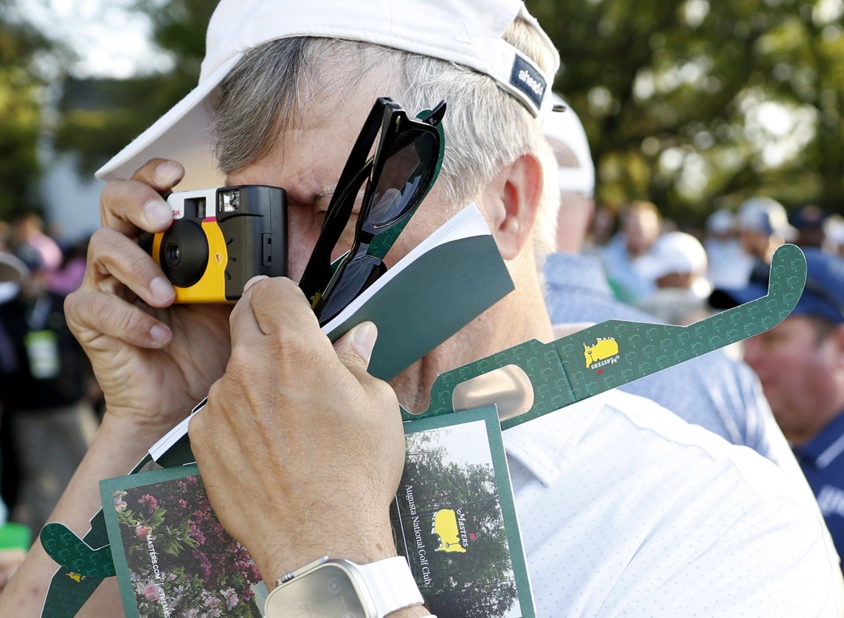 A patron holds sunglasses, souvenirs and Masters brand solar eclipse glasses during a practice round before the Masters Tournament at Augusta National Golf Club in Augusta, Georgia on Monday, April 8, ...