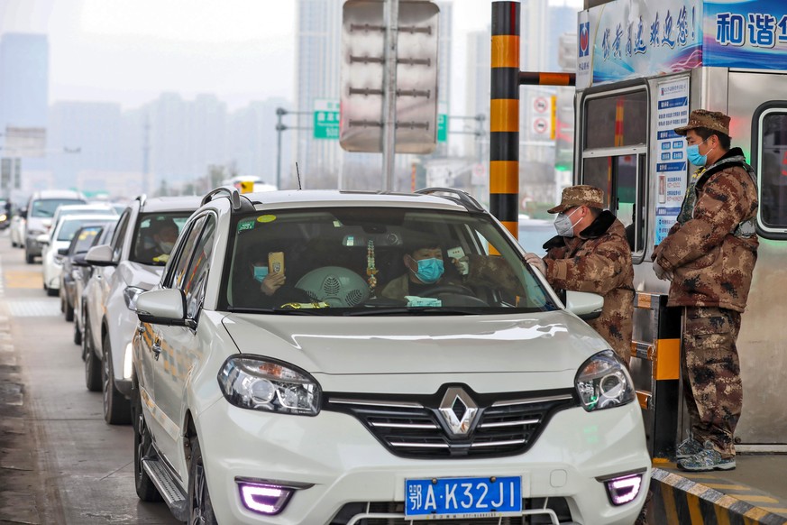 epa08154640 A militia member checks the body temperature of a passenger on a vehicle at an expressway toll gate in Wuhan, central China's Hubei province, 23 January 2020. Wuhan has shut down publ ...