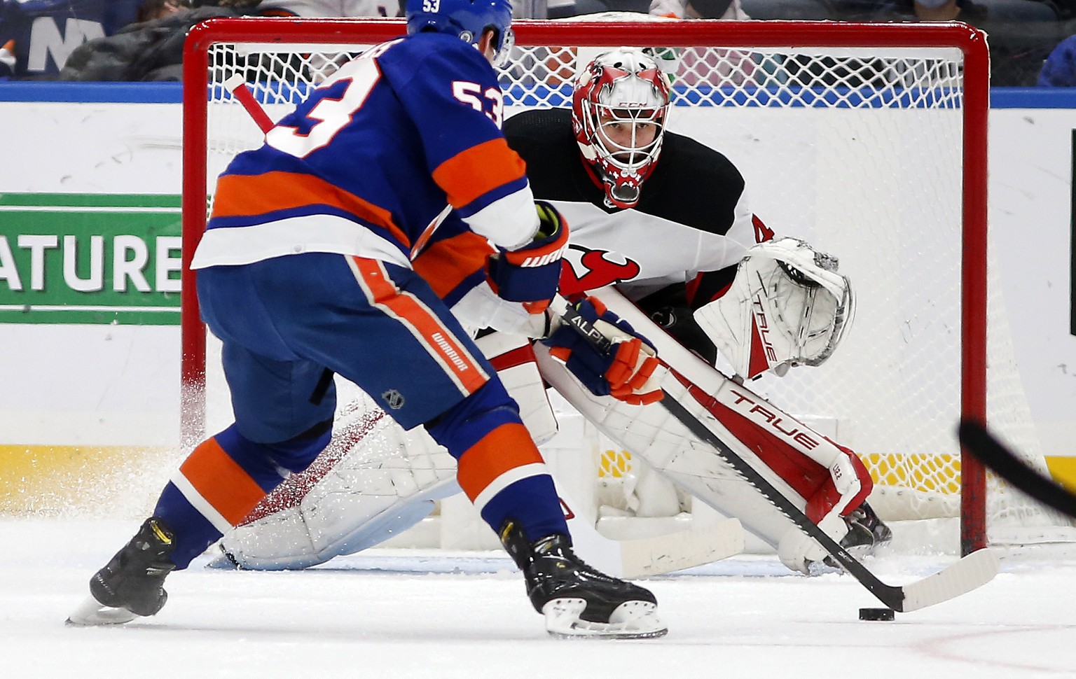 New Jersey Devils goaltender Akira Schmid (40) defends the net during the first period of an NHL hockey game against New York Islanders center Casey Cizikas (53) on Saturday, Dec. 11, 2021, in Elmont, ...
