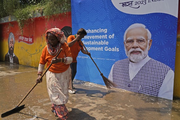 Municipal workers clean a side walk near a billboard featuring Indian Prime Minister Narendra Modi ahead of this week&#039;s summit of the Group of 20 nations, in New Delhi, India, Thursday, Sept. 7, ...