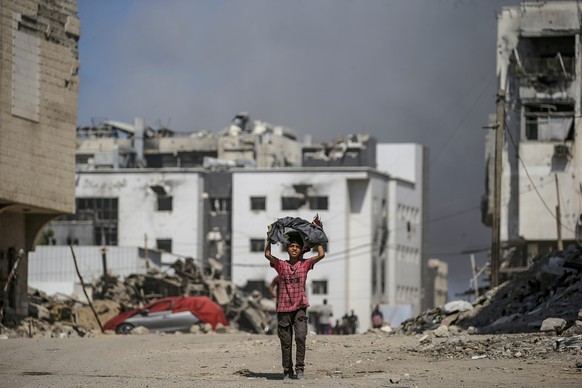 epa12412366 A Palestinian boy walks as smoke rises following an Israeli airstrike around Al-Shifa hospital in Gaza City, Gaza Strip, 28 September 2025. More than 66,000 Palestinians have been killed i ...