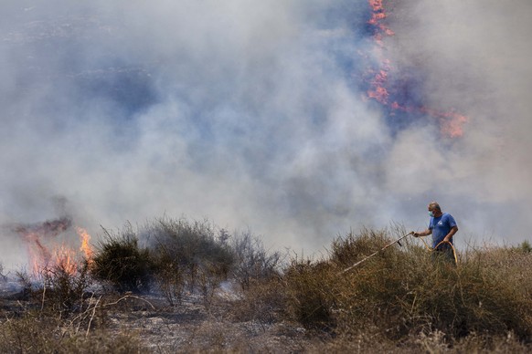 An Israeli worker from the Nature and Parks Authority attempts to extinguish a fire caused by a incendiary balloon launched by Palestinians from the Gaza Strip, on the Israeli side of the border betwe ...