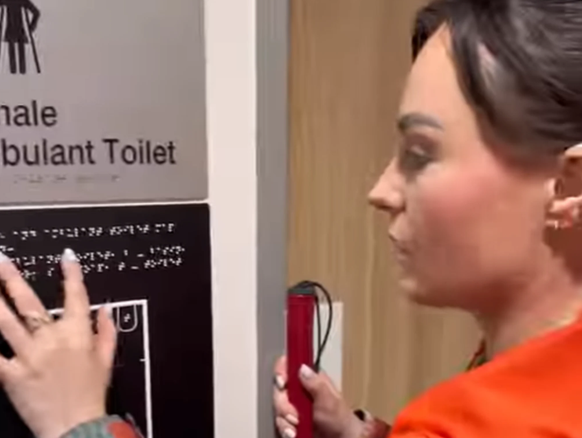 Die blinde Influencerin Molly Burke präsentiert in einem Instagram-Video den taktilen Raumplan eines öffentlichen Toilettenraums.