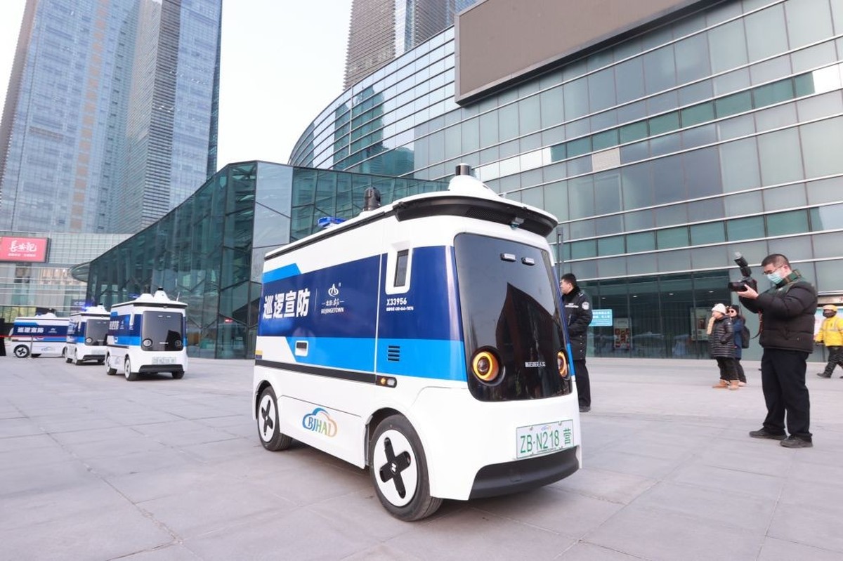 BEIJING, CHINA - JANUARY 16: A citizen takes photos of unmanned patrol vehicles during their road test on January 16, 2024 in Beijing, China. The first batch of unmanned patrol vehicles in China begin ...