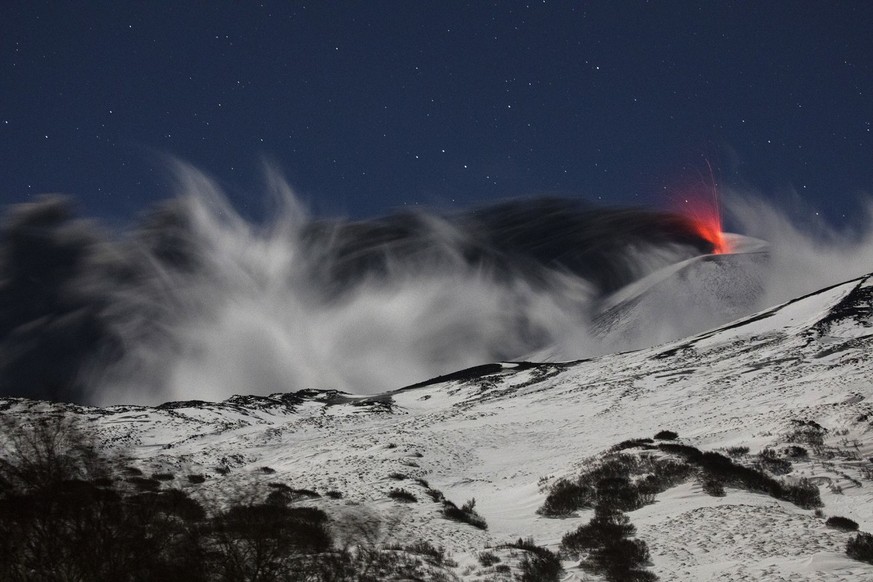 Mount Etna during its explosive eruption in December 2021. The explosive pyroclastic material erupts with a black cloud of volcanic sand, against a dark sky that provides a stunning contrast...