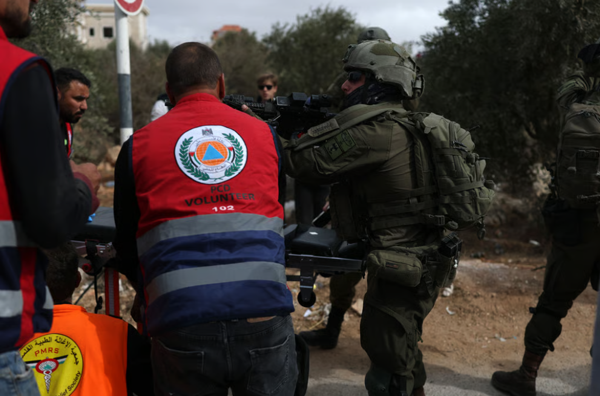 Israelische Soldaten und palästinensische Helfer umringen einen verletzten Bauern nach einer Siedlerattacke im Westjordanland.