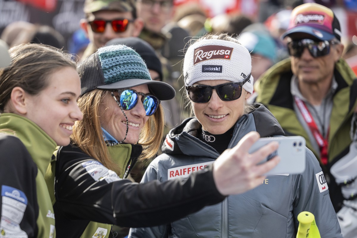Lara Gut-Behrami of Switzerland, center, with her father and coach Pauli Gut, right, stands for selfies with fans, in the finish area during the women's Super G race at the Alpine Skiing FIS Ski  ...