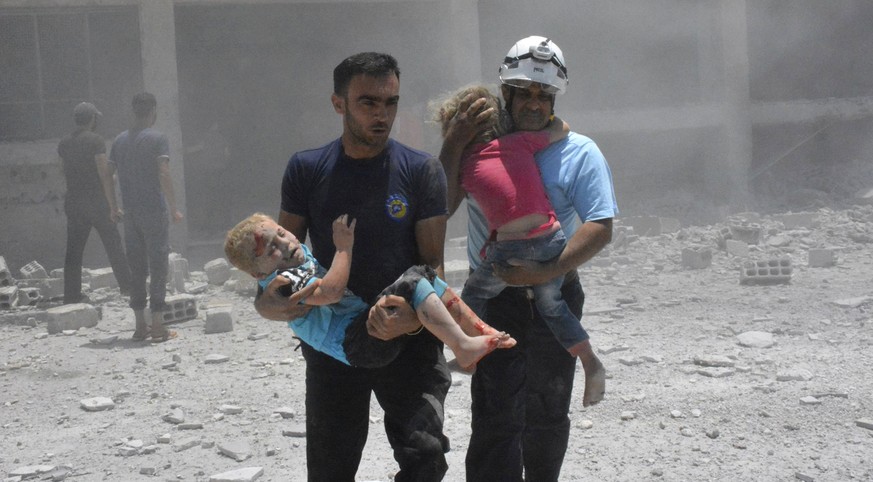 FILE - In this Wednesday, June 14, 2017, file photo, provided by the Syrian Civil Defense group known as the White Helmets, shows civil defense workers carrying children after airstrikes hit a school  ...