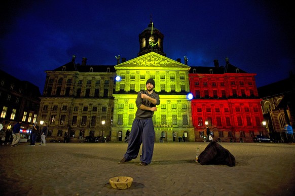 epa05226318 The Royal Palace at Dam Square in Amsterdam, is seen with the black, yellow and red colours of the Belgian flag in tribute to the victims of the Brussels terror attacks that occured earlei ...