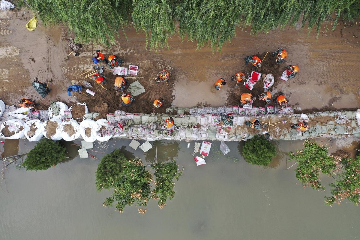 In this photo released by Xinhua News Agency, an aerial photo shows rescuers fortifying a temporary dyke against the flooding at the Lianbo Village in Hejin City, in northern China's Shanxi Provi ...
