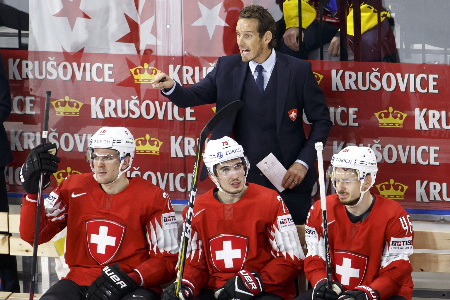 Patrick Fischer, head coach of Switzerland national ice hockey team, gestures behind his players defender Joel Genazzi, left, forward Damien Riat, center, and forward Noah Rod, right, during the IIHF  ...