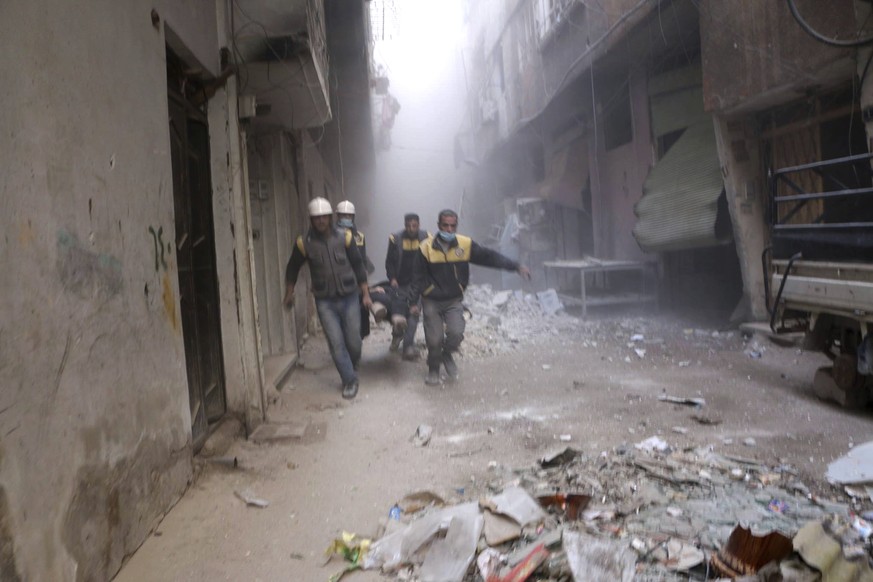 This photo released on Friday, Feb. 23, 2018 provided by the Syrian Civil Defense group known as the White Helmets, shows members of the Syrian Civil Defense group carrying a man who was wounded durin ...