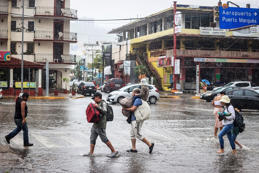 epa10803596 People walk through a flooded street due to heavy rains in the resort of Acapulco, Guerrero state, Mexico, 16 August 2023. Mexico expects tropical storm Hilary, the eighth named cyclone of ...
