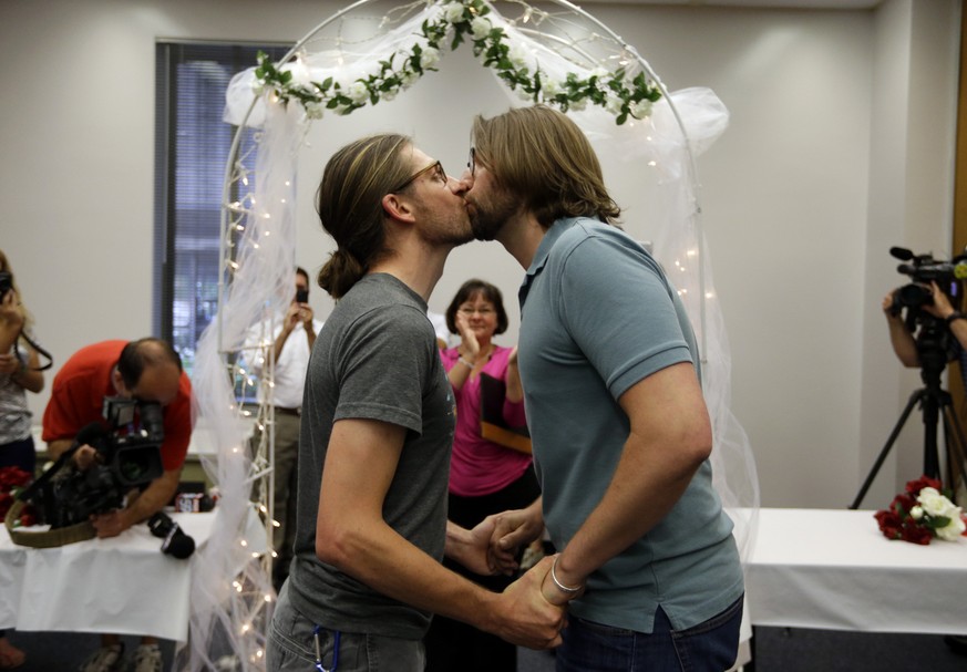 Jake Miller, 30, and Craig Bowen, 35, right, kiss after being married by Marion County Clerk Beth White, center, in Indianapolis, Wednesday, June 25, 2014. A federal judge struck down Indiana&#039;s b ...