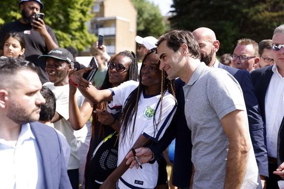 Roger Federer with local school children at the opening of newly refurbished park tennis courts at Bostall Gardens in Greenwich, London, Thursday June 15, 2023. (Steven Paston/PA via AP)