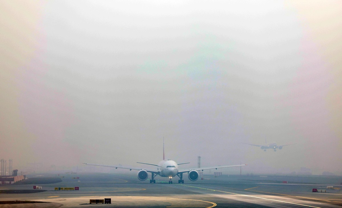 epa12724067 A photo taken from behind airplane's window glass shows a commercial airplanes owned by Emirates Airlines preparing to take off (C) and other one (R) landing at Dubai International Ai ...