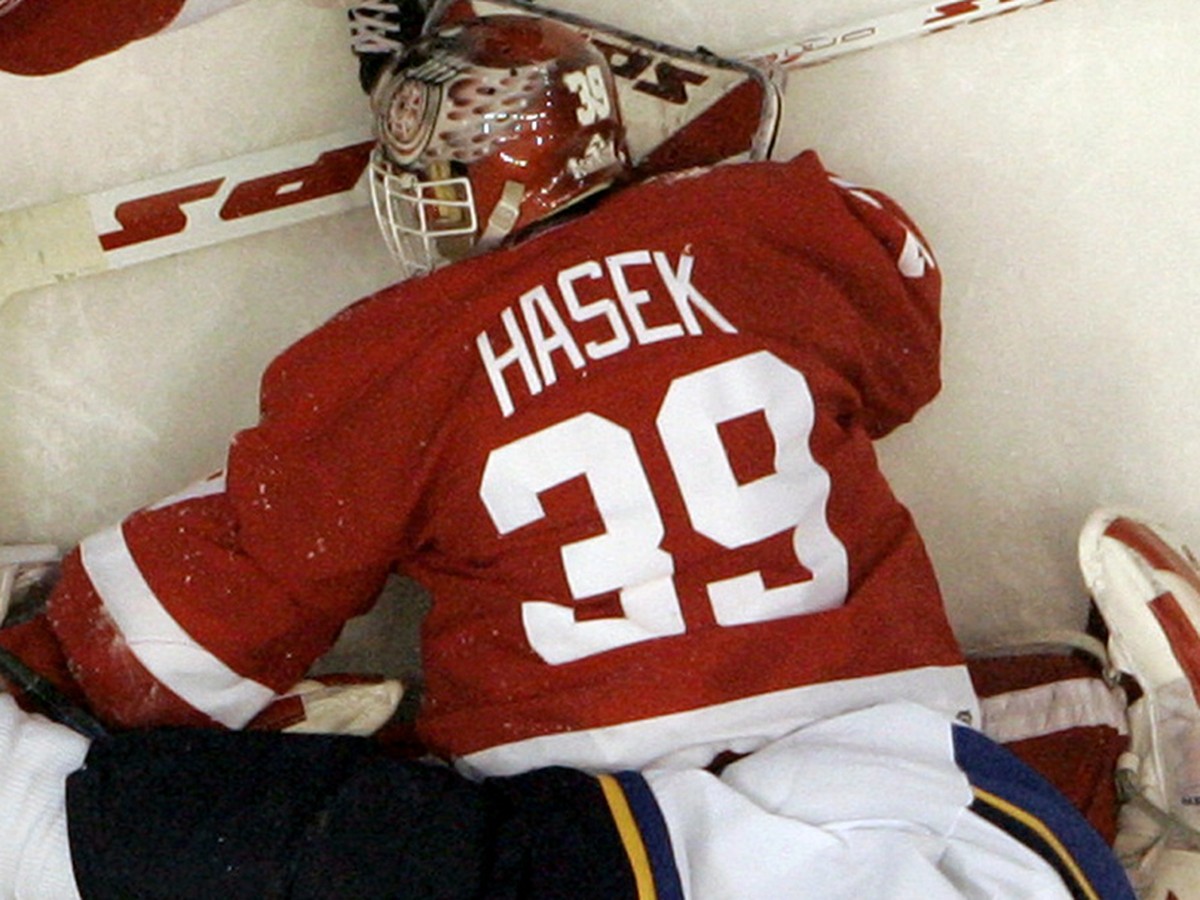 Detroit Red Wings goalie Dominik Hasek, of the Czech Republic, searches for the puck as St. Louis Blues defenseman Eric Brewer (4) lands on him during the third period of Detroit's 5-3 win in an  ...