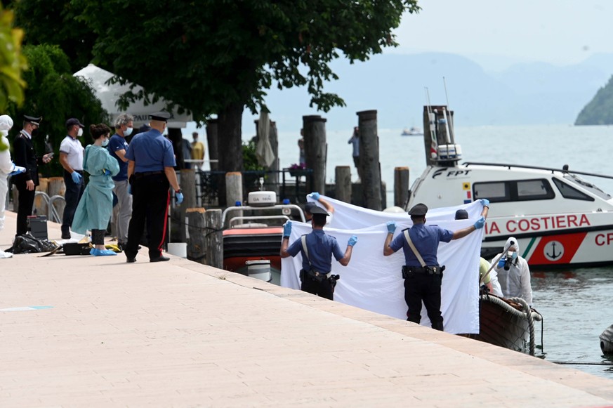Italian police hold up a white sheet as forensic police inspect a boat as they investigate two German tourists from Munich for a boat collision which killed an Italian man and woman, in Salo&#039;, on ...