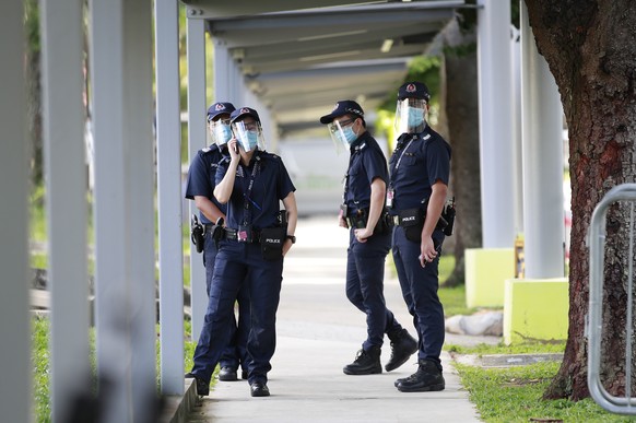 epa08517095 Police officers wearing protective face shields patrol a walkway before the arrival of candidates at a nomination centre in Singapore, 30 June 2020. Candidates standing for the 18th genera ...