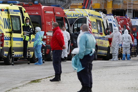 Ambulance personnel stand waiting as more than a dozen ambulances queue waiting to hand over their COVID-19 patients to medics at the Santa Maria hospital in Lisbon, Friday, Jan. 22, 2021. Portugal&#0 ...