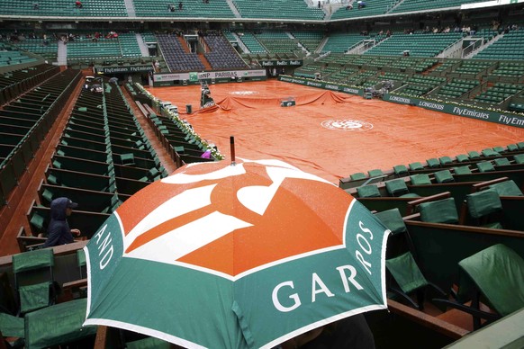 Spectators protect themselves from the rain with an umbrella on the Philippe Chatrier court during a delay as they follow the women&#039;s singles match between Ekaterina Makarova of Russia and Ana Iv ...