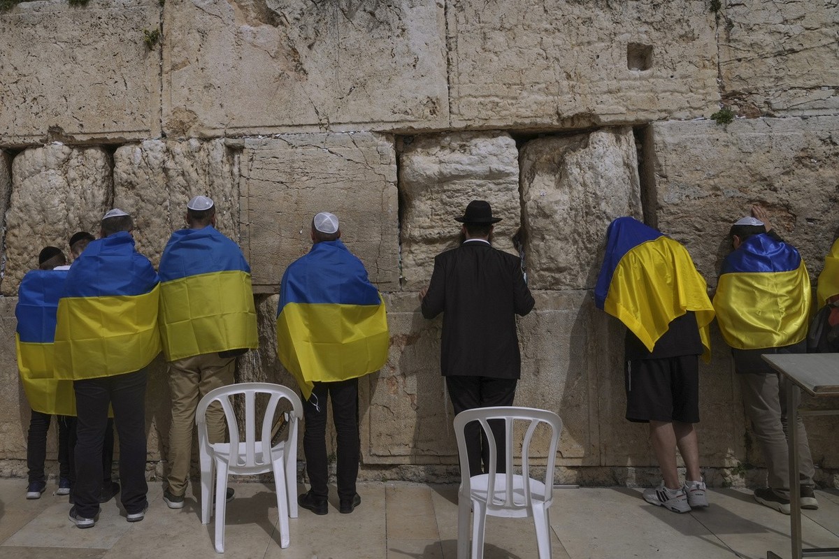 Ukrainian delegation from Kyiv wrapped in Ukrainian flags pray at the Western Wall, the holiest site where Jews can pray in Jerusalem's Old City, Friday, April 1, 2022. Ukrainian ambassador to Is ...