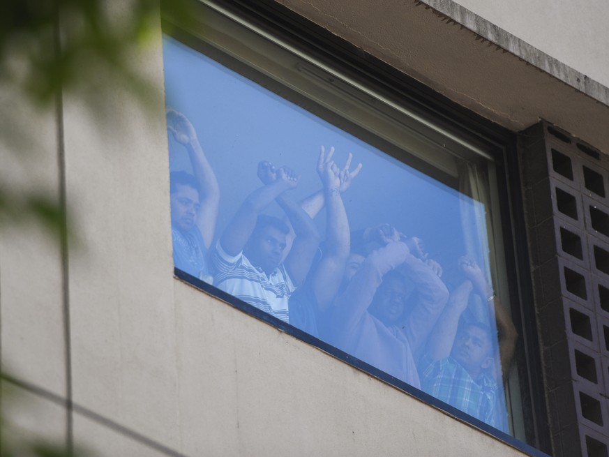 epaselect epa08927513 Refugees gesture towards protesters at the Park Hotel in Melbourne, Australia, 09 January 2021. Around 60 refugees and asylum seekers are being detained at the Park Hotel in Melb ...