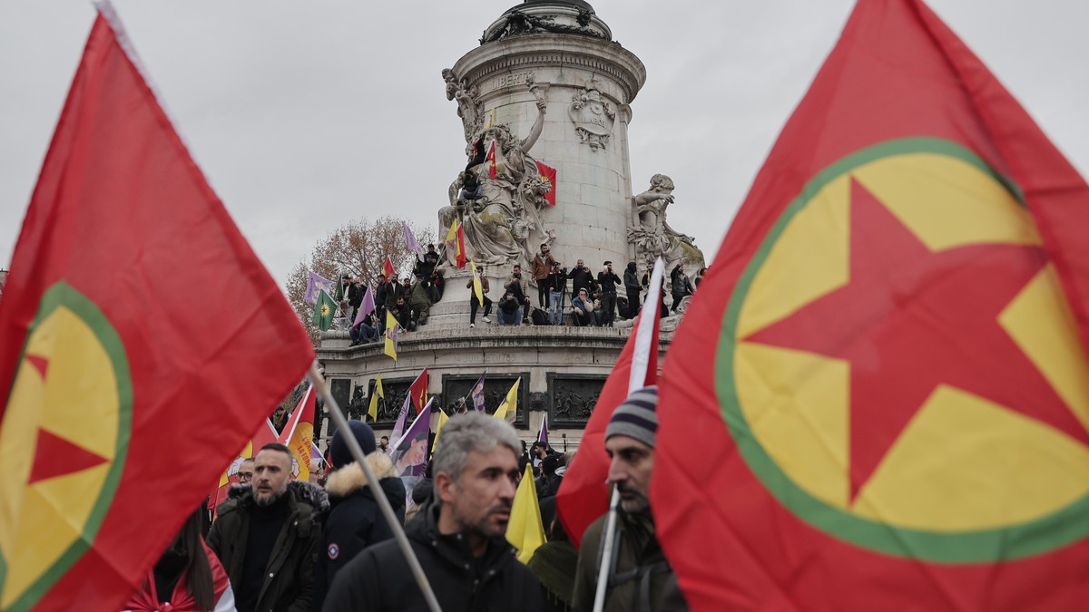 Kurdish activist holding Kurdistan Workers Party, PKK, flag stage a protest against the recent shooting at the Kurdish culture center next to the Republique square statue at in Paris, Saturday, Dec. 2 ...