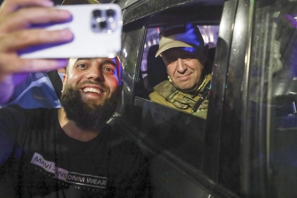 Yevgeny Prigozhin, the owner of the Wagner Group military company, right, sits inside a military vehicle posing for a selfie photo with a local civilian on a street in Rostov-on-Don, Russia, Saturday, ...