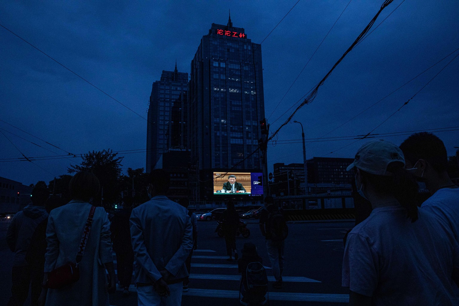 Passanten in Peking verfolgen auf einem Grossbildschirm, wie der Nationale Volkskongress tagt.
