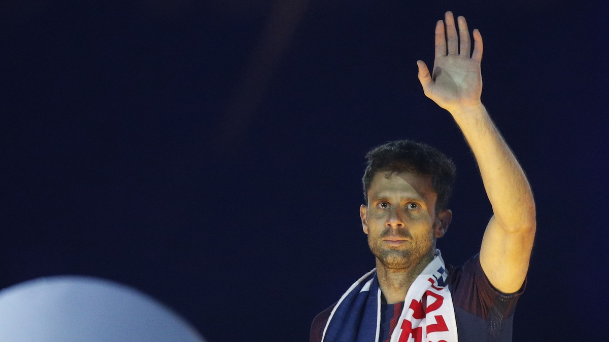PSG's Thiago Motta waves to fans next to the League One trophy after the soccer match between Paris Saint-Germain and Stade Rennais at the Parc des Princes stadium in Paris, Saturday May 12, 2018 ...