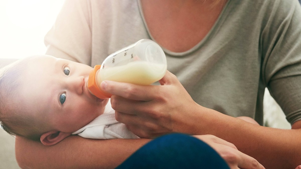 Babynahrung, Baby, Milch, Babymilch, Flasche, Nestlé, Hochdorf, Mom, milk and feeding baby in living room for growth development, nutrition or digestive health. Lens flare, formula and woman with infa ...