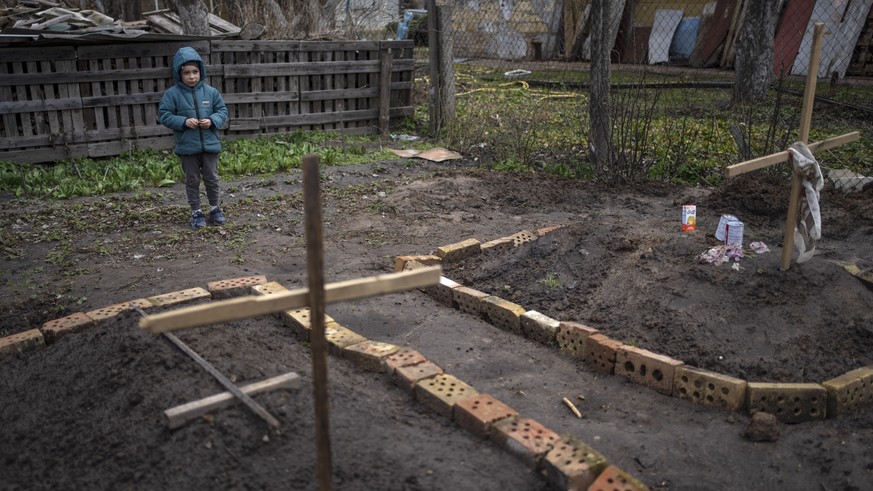 In the courtyard of their house, Vlad Tanyuk, 6, looks at the grave of his mother Ira Tanyuk, who died because of starvation and stress due to the war, in Bucha, on the outskirts of Kyiv, Ukraine, Mon ...