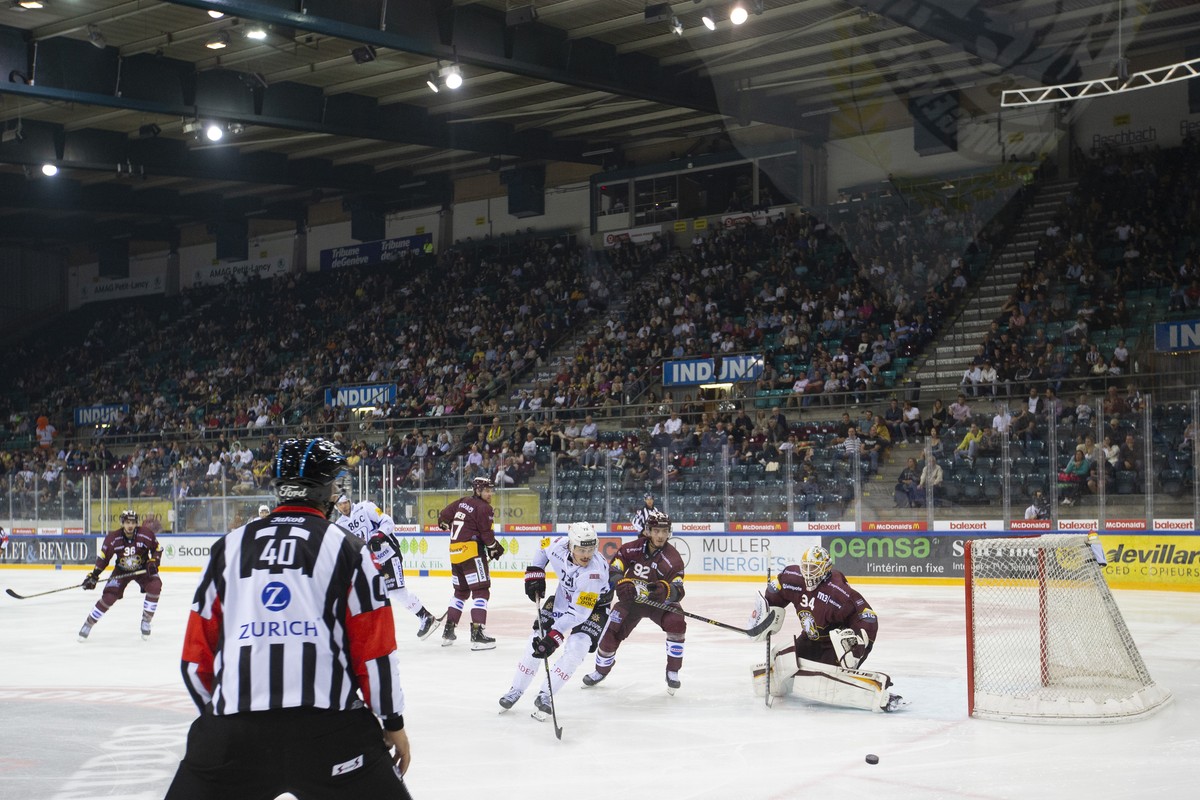 Fribourg's forward Sandro Schmid, left, vies for the puck with Geneve-Servette's forward Eliot Berthon, center, past Geneve-Servette's goaltender Gauthier Descloux, right, during a Nati ...