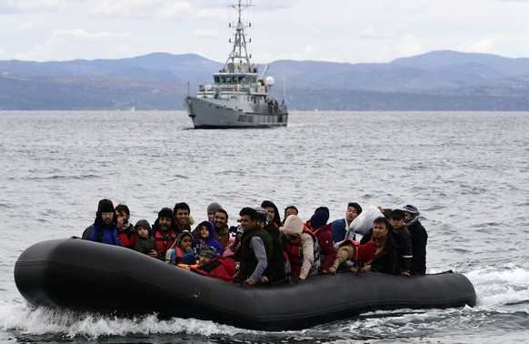 FILE - In this Friday Feb. 28, 2020 file photo, refugees and migrants arrive in a dinghy accompanied by Frontex vessels at the village of Skala Sikaminias, on the Greek island of Lesbos, after crossin ...