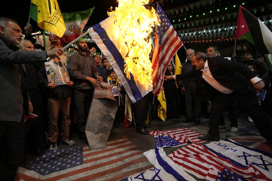 Iranian protesters burn representations of the U.S. and Israeli flags during their gathering to condemn killing members of the Iranian Revolutionary Guards in Syria, at the Felestin (Palestine) Sq. in ...