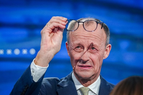 epa11901915 Christian Democratic Union (CDU) party leader and chancellor candidate Friedrich Merz checks his glasses during the TV debate &#039;Quadrell&#039; on the German federal election campaign,  ...
